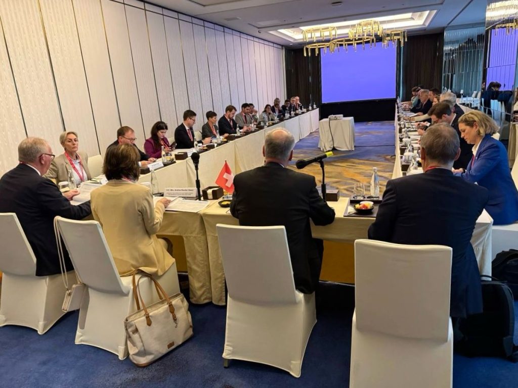 The Swiss Delegation sitting around a "U-table", with FC Parmelin seen from behind.